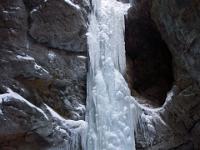 Hoher vereister Wasserfall neben Höhle